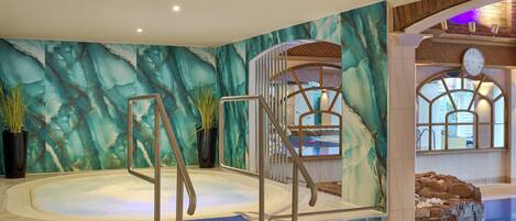 Un área de jacuzzi con un fondo de pared de mármol, una escalera de madera y una piscina con un reloj.