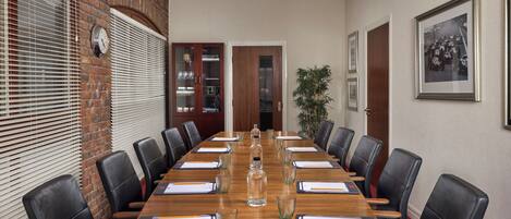 A conference room with a long table, black leather chairs, and a clock on the wall.