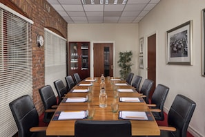 A conference room with a long table, black leather chairs, and a clock on the wall.
