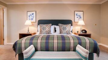 A neatly made bed with a plaid bedspread and matching pillows, flanked by two bedside tables with lamps and framed artwork on the walls.