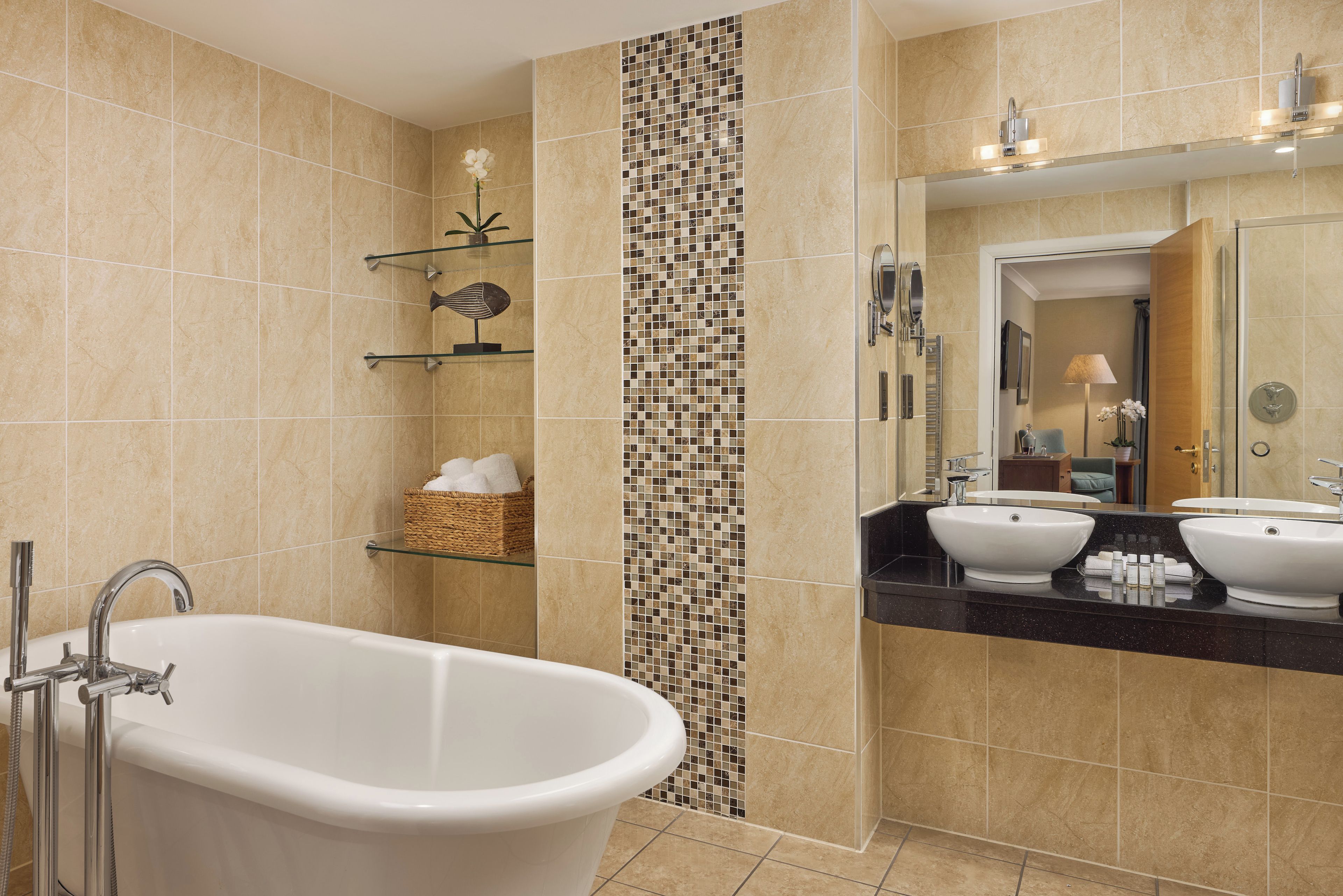 A modern bathroom with a freestanding bathtub, two sinks, and a large mirror.