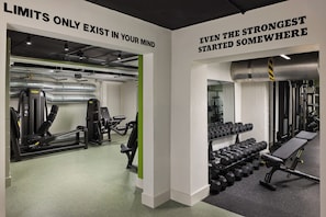 A gym with exercise equipment, weight racks, and motivational wall quotes.
