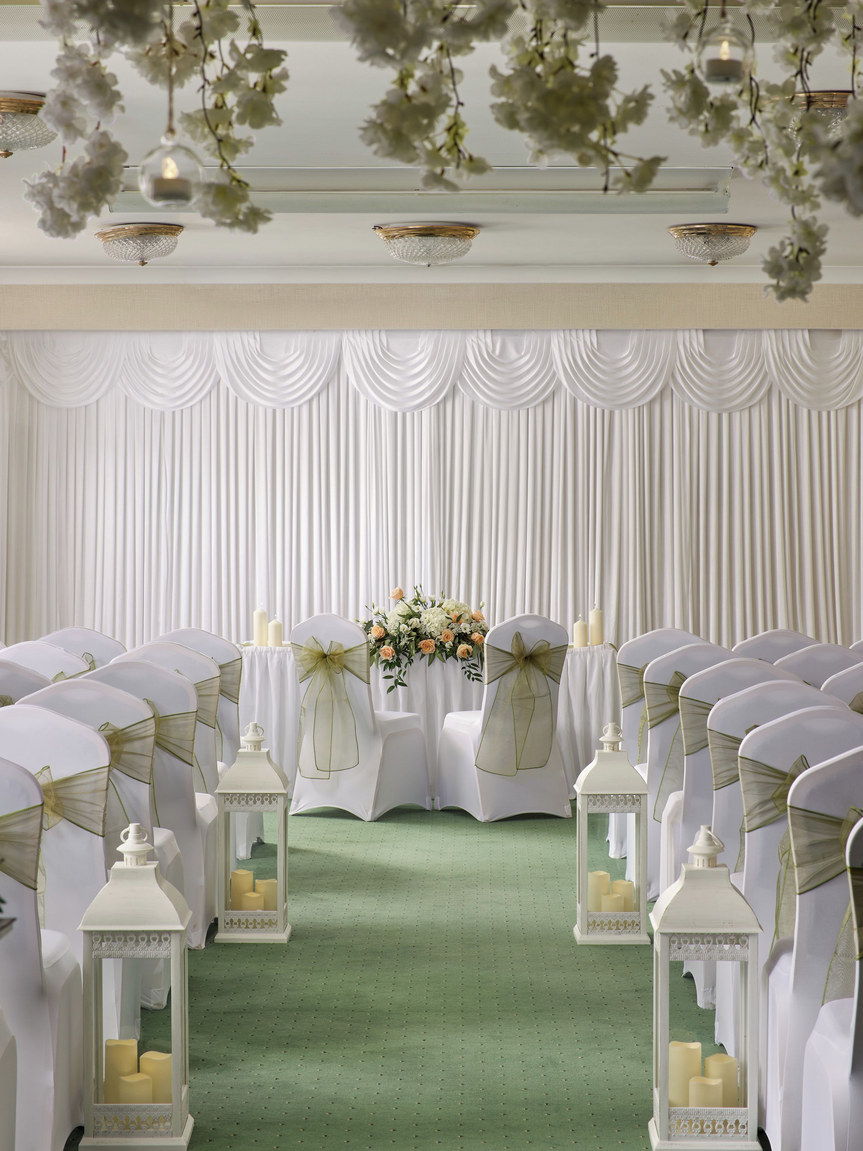 A formal event space with rows of chairs, a floral centerpiece, and decorative lanterns.