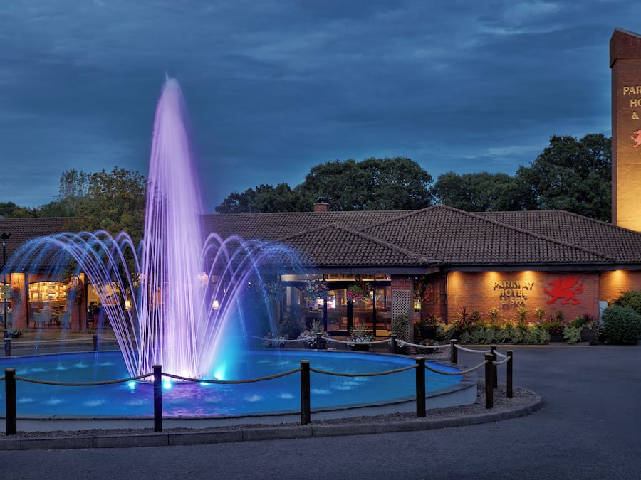 Un hotel con una fuente en primer plano, un edificio de ladrillo y un cartel que indica Parkway Hotel & Spa.