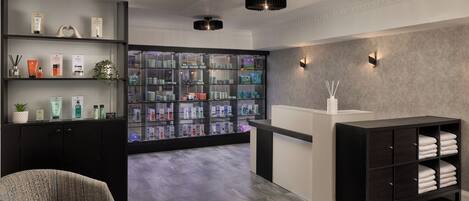 A modern bathroom with a glass display of toiletries, a towel rack, and a seating area.