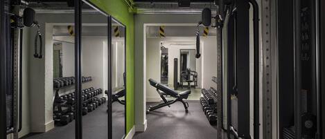 A gym with exercise equipment, mirrored walls, and a green accent wall.