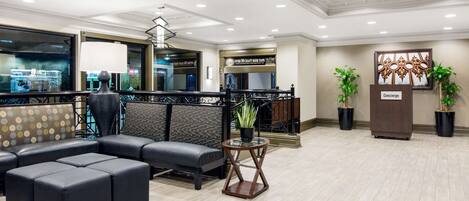 A modern lobby with a sectional sofa, a reception desk, and potted plants.