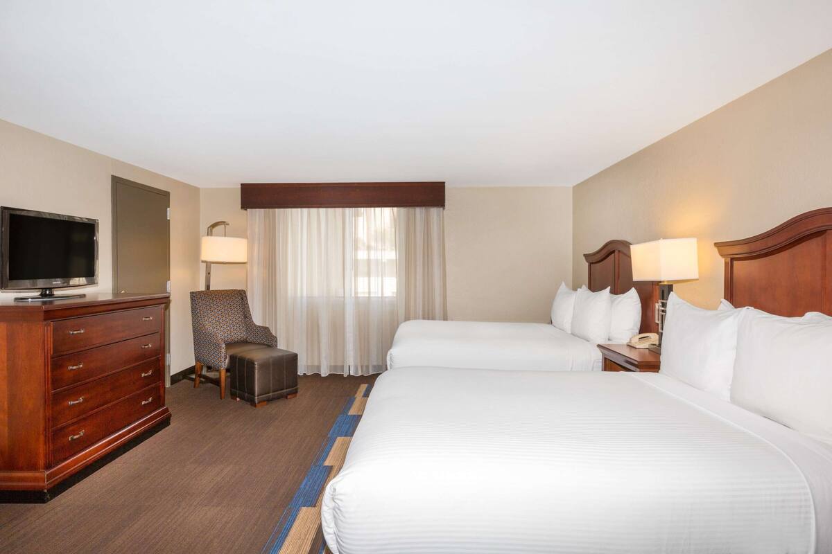 Een hotelkamer met een groot bed, een televisie, een bureau en een stoel.