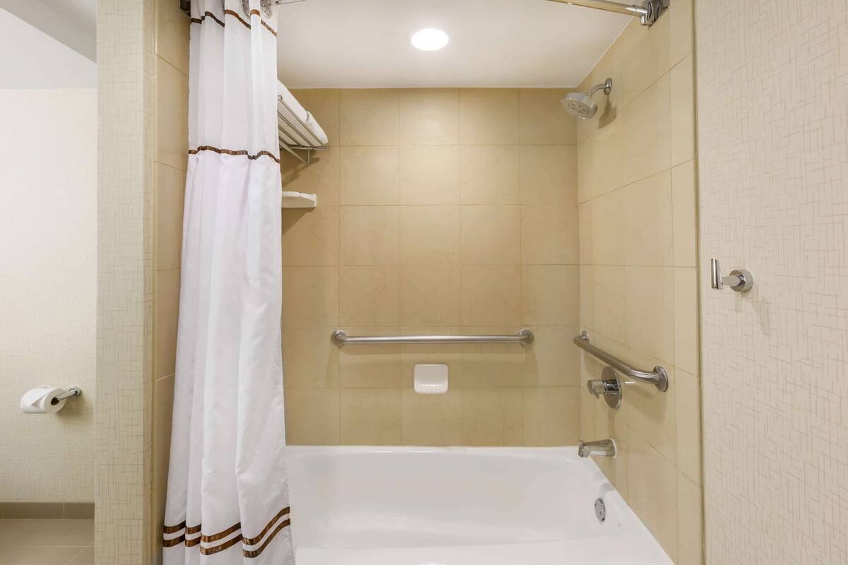Een badkamer met een bad, douche en toilet.