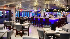 Een restaurant met een bar, tafels en stoelen.