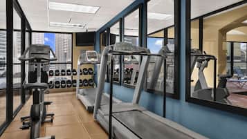A gym with treadmills, weight machines, and dumbbells.