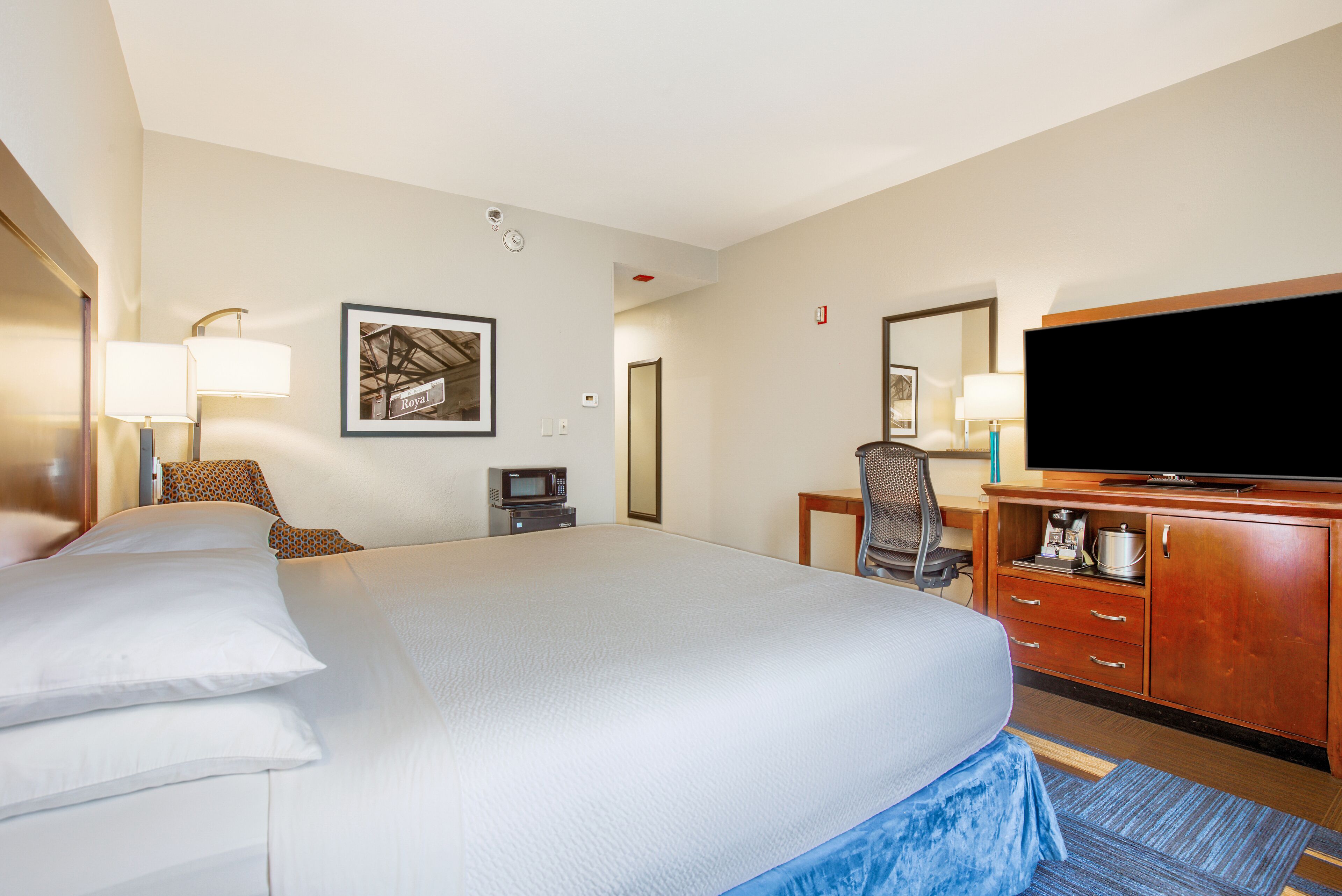 A hotel room with a large bed, a desk with a computer, a television, and a microwave.