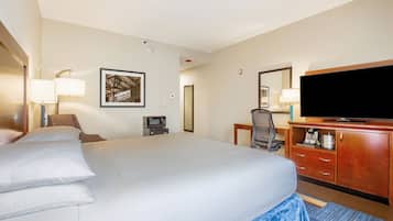A hotel room with a large bed, a desk with a computer, a television, and a microwave.