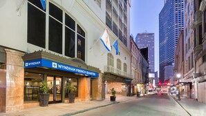 Een hotel met een bord dat ‘French Quarter’ aangeeft, grote ramen en bloempotten buiten.