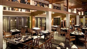 Un restaurante espacioso con varias zonas de comedor, mobiliario de madera y un techo alto con vigas a la vista.