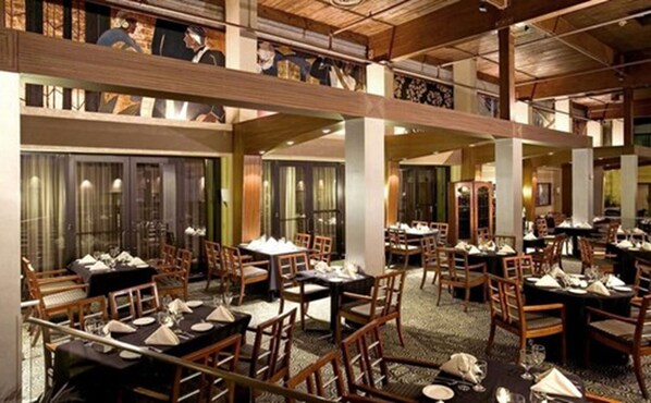 A spacious restaurant with multiple dining areas, wooden furniture, and a high ceiling with exposed beams. - Radisson Hotel Hauppauge-Long Island (Hauppauge)
