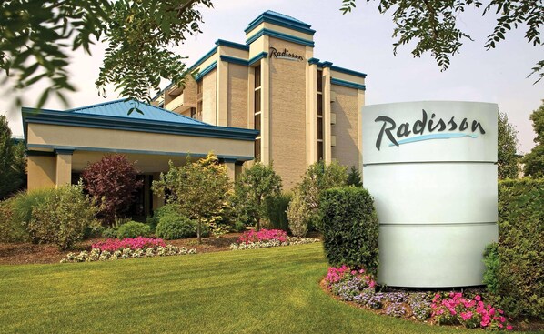 Un hotel Radisson con un letrero grande, rodeado de jardines y árboles bien cuidados.