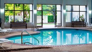 Una piscina con borde de azulejos, bancos y sillas de descanso.