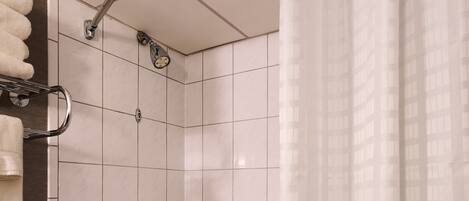 A bathroom with a bathtub, a shower, and a toilet. There are white tiles on the walls and a shower curtain.