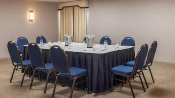 A conference room with a round table, blue chairs, and a carpeted floor.