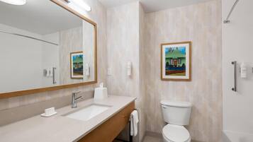 A modern bathroom with a large mirror, a sink, a toilet, and a bathtub.