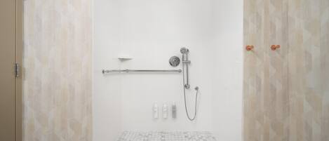 A walk-in shower with a glass door, a handheld showerhead, a handheld shower attachment, and a towel rack.