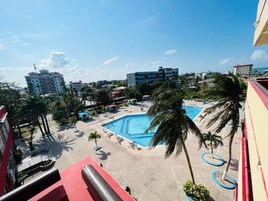 Una piscina rodeada de palmeras y edificios, con cielo despejado.