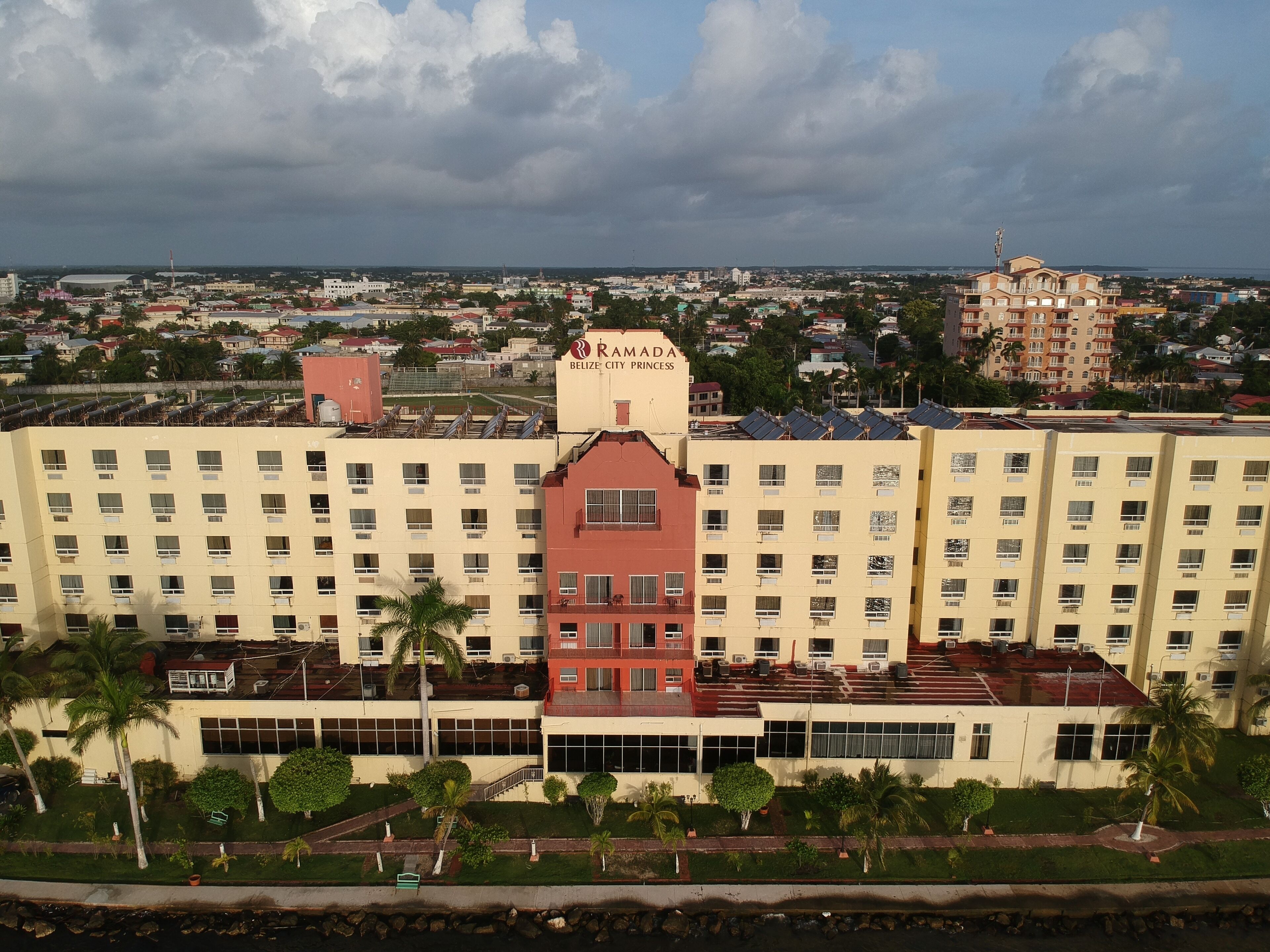 A multi-story hotel with a central red tower, surrounded by uniform buildings, and a view of a distant cityscape.