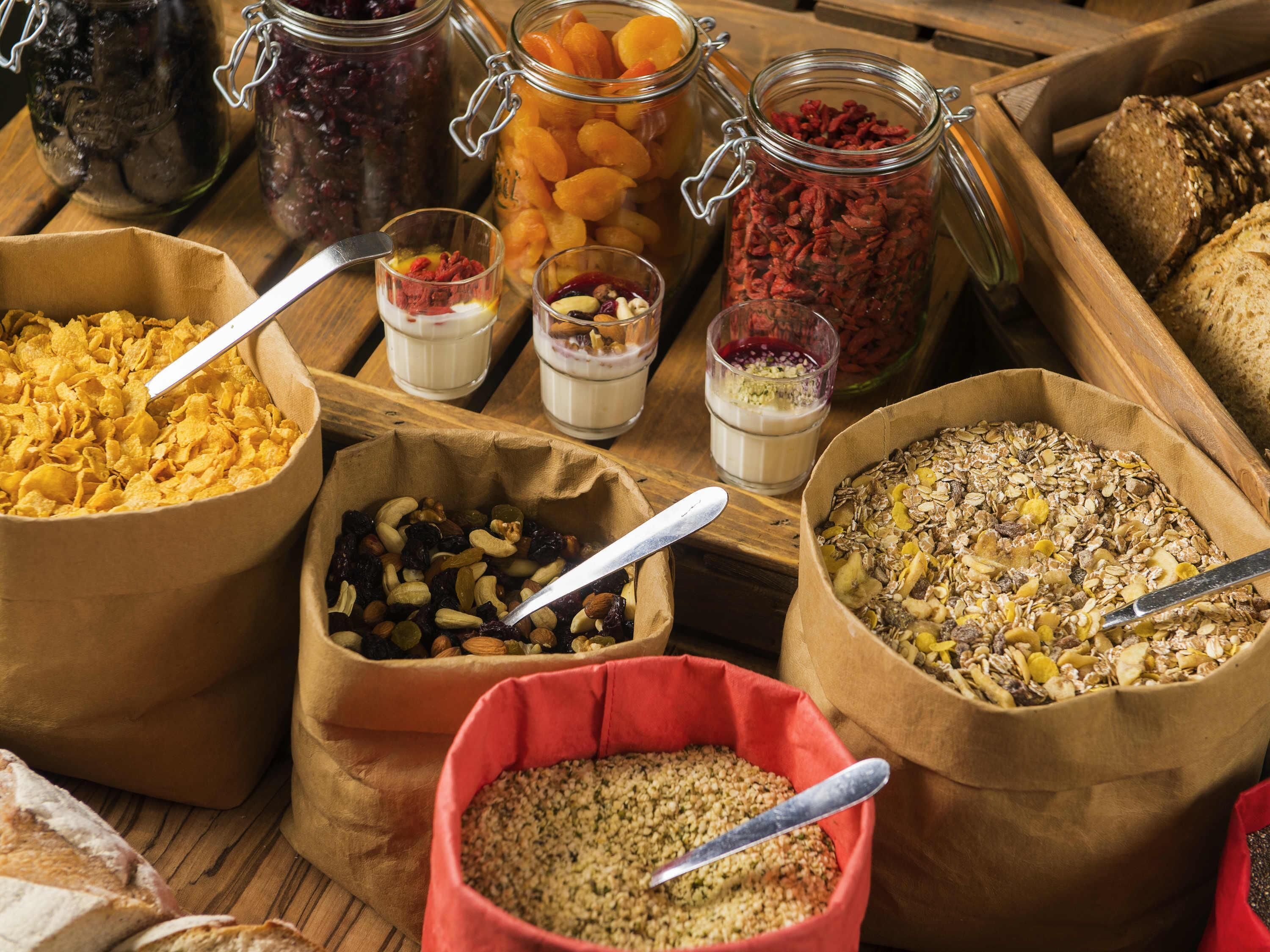Diversos alimentos en recipientes, como frutas secas, frutos secos y granola.