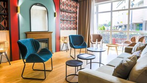 Een moderne lounge met een open haard, zithoek en grote ramen met uitzicht op de straat.