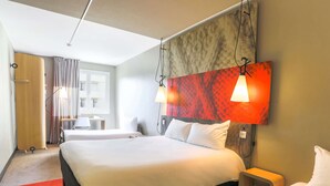 Een hotelkamer met een groot bed, nachtkastjes, een bureau en een stoel.