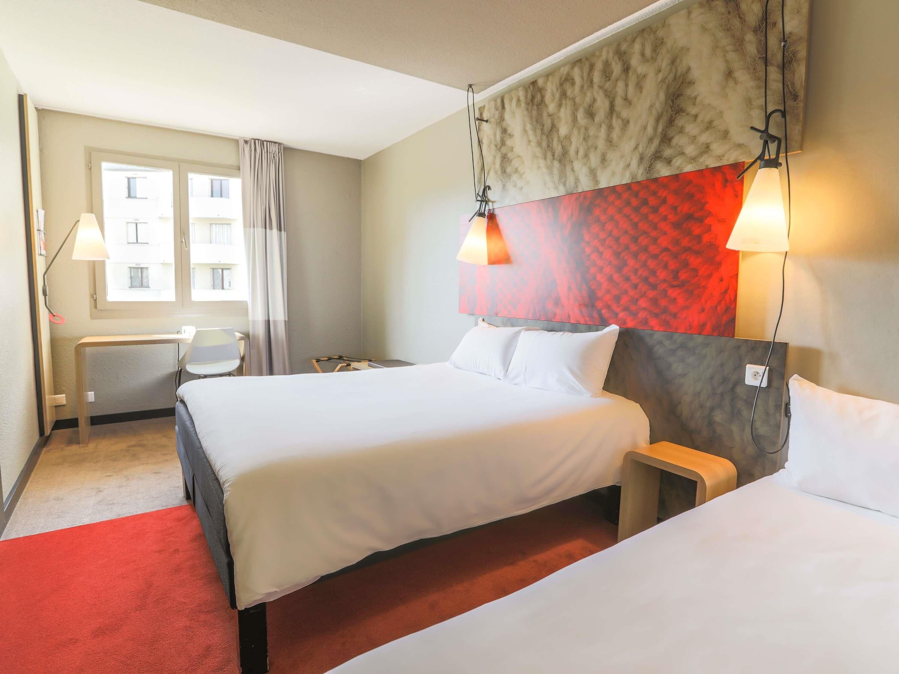 Une chambre d’hôtel avec deux lits, un bureau et une chaise.