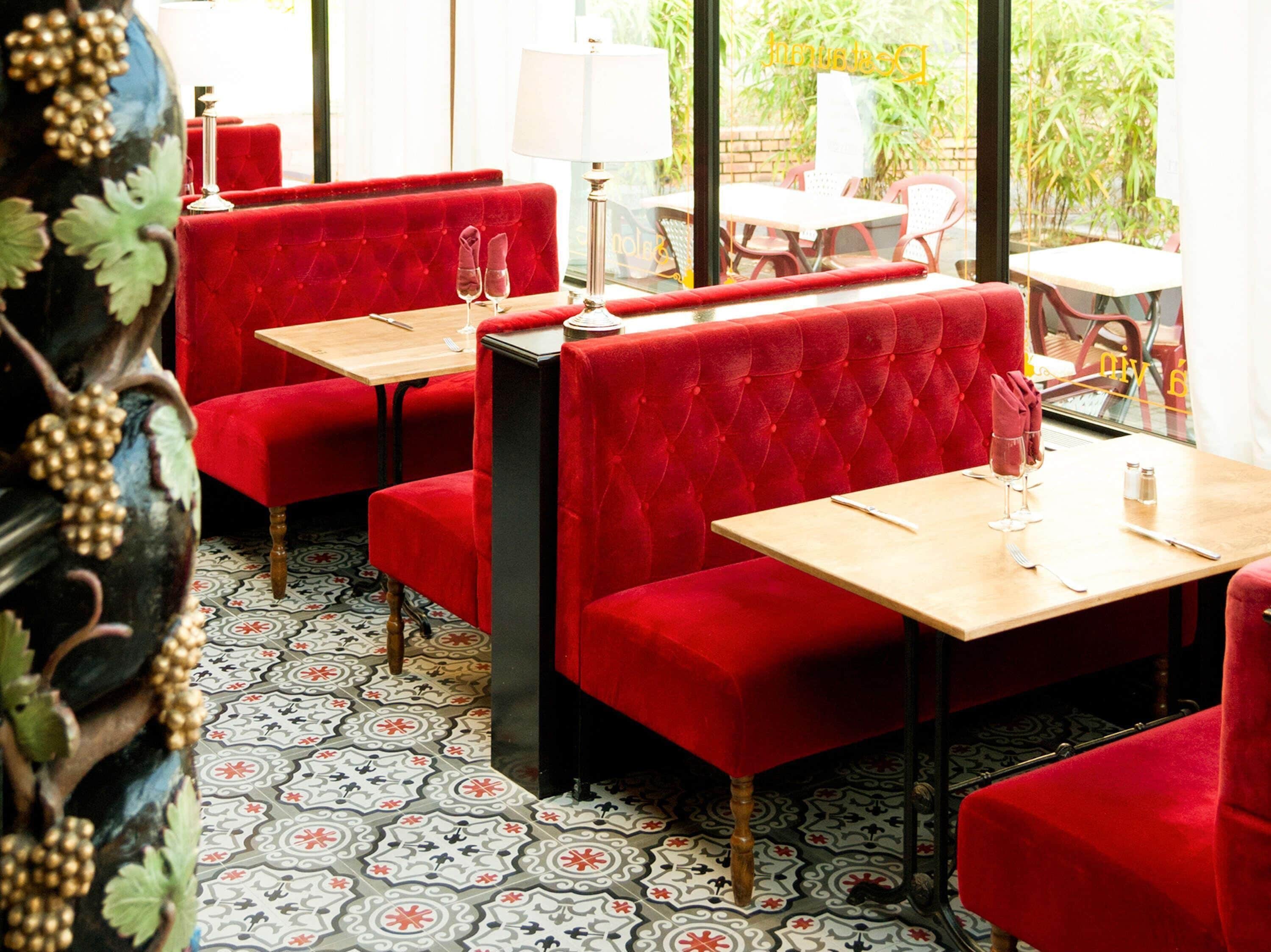A restaurant with red upholstered booths, wooden tables, and patterned floor tiles.