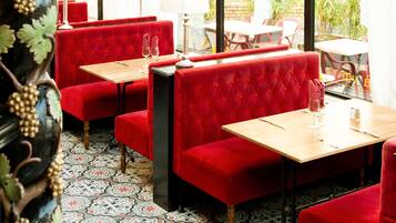 A restaurant with red upholstered booths, wooden tables, and patterned floor tiles.