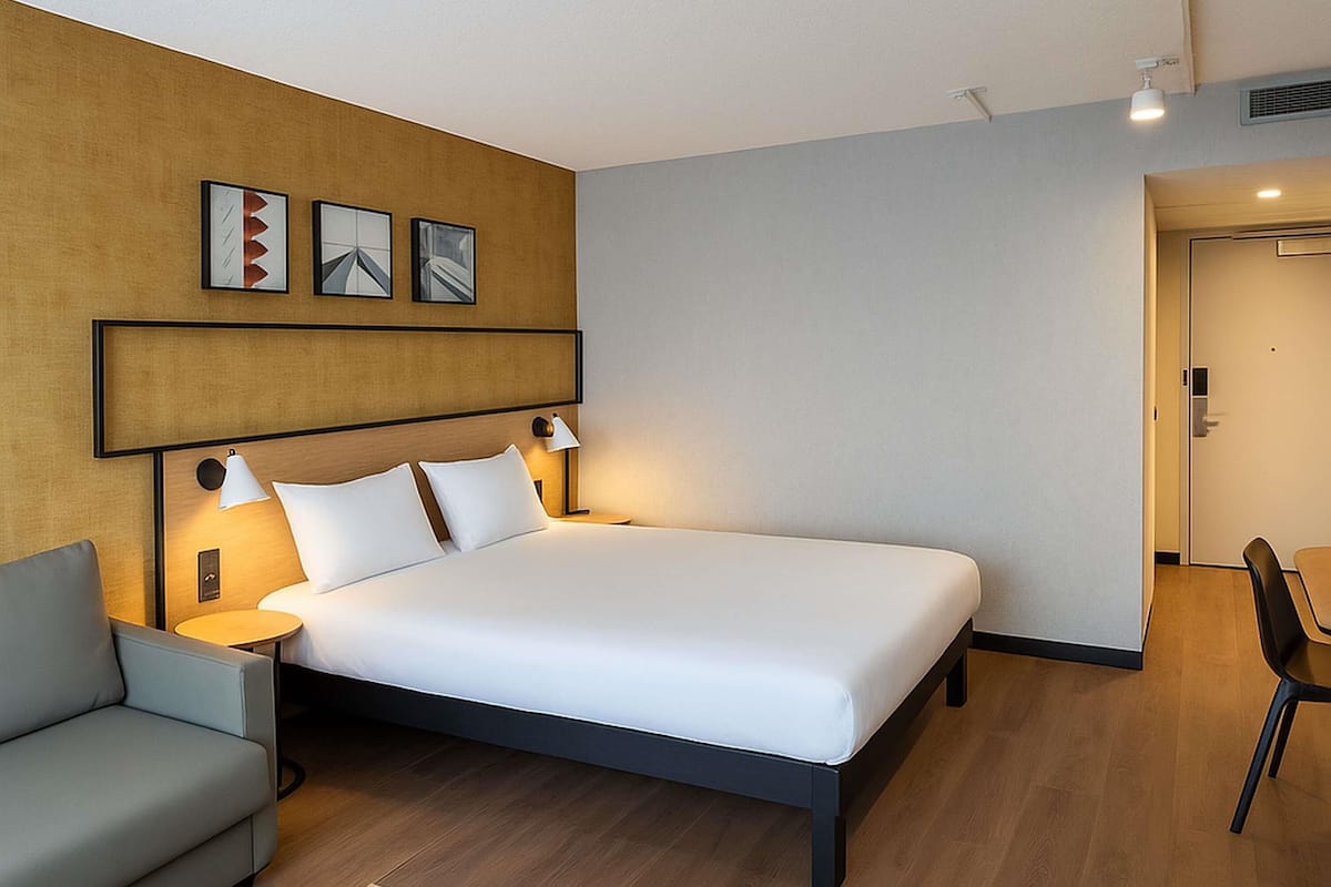 Une chambre d’hôtel avec un lit, un canapé, un bureau et une porte.