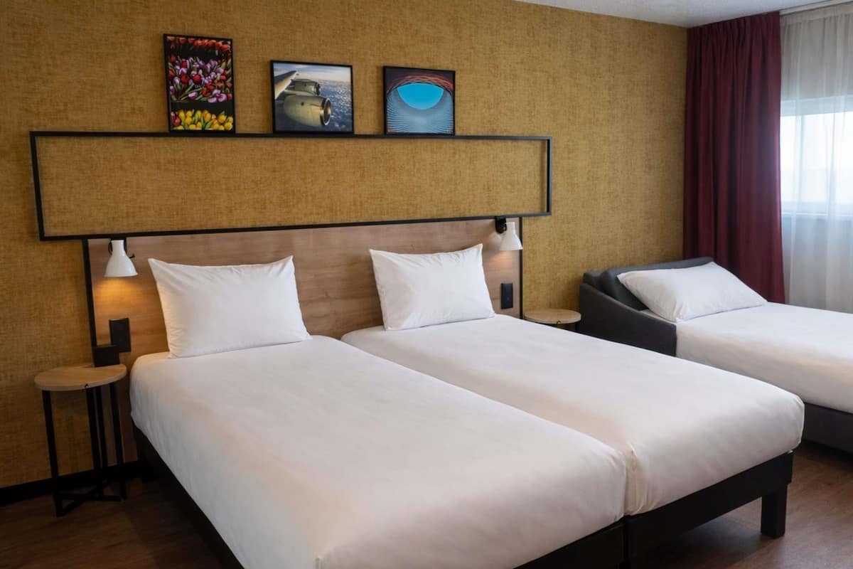 Une chambre d’hôtel avec deux lits, une grande tête de lit et des œuvres d’art accrochées au mur.