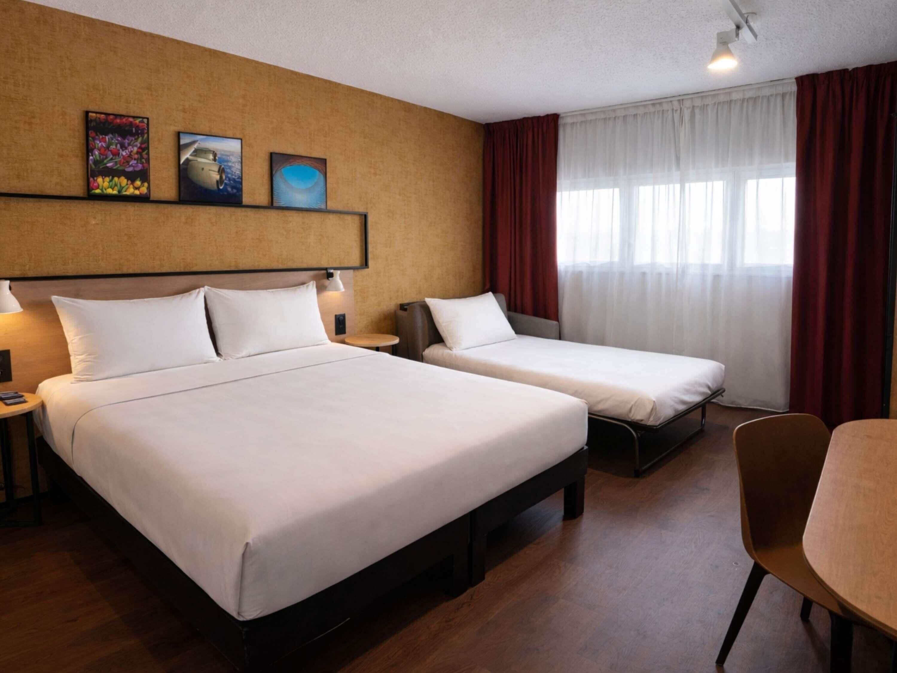 Ein Hotelzimmer mit zwei Betten, einem Schreibtisch und einem Stuhl.