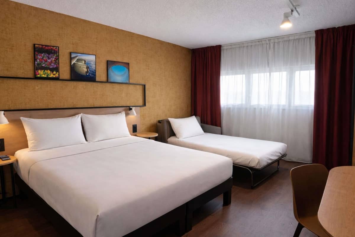 Ein Hotelzimmer mit zwei Betten, einem Schreibtisch und einem Stuhl.