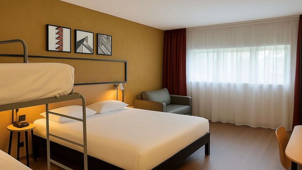 A hotel room with a bunk bed, a single bed, a desk, a chair, a sofa, and a window with curtains. - Ibis Rungis Aéroport Paris Orly (Rungis)