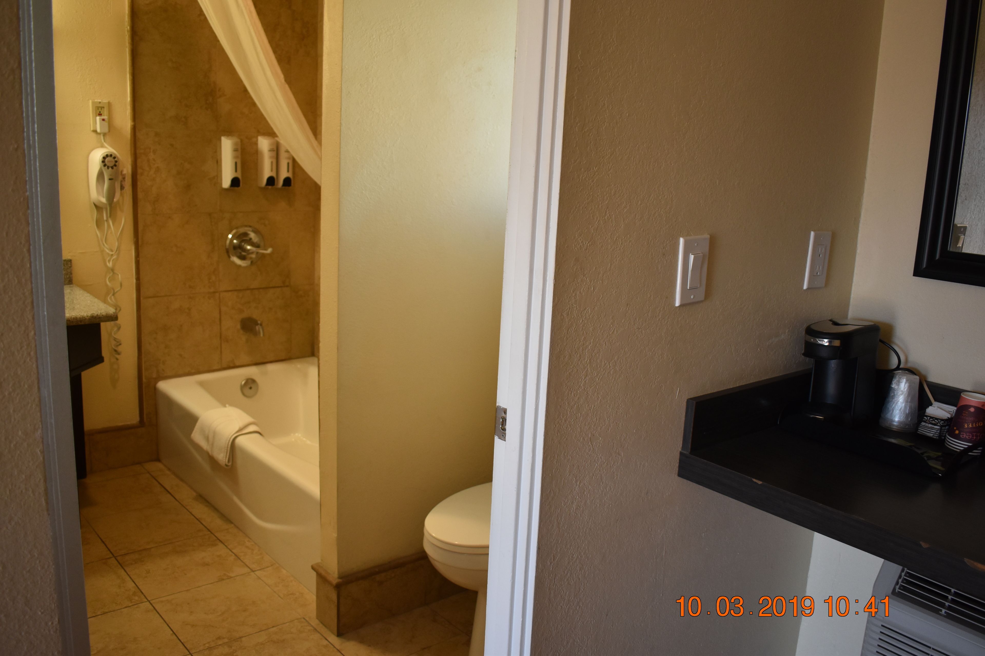 A bathroom with a bathtub, toilet, and a sink with a coffee maker.