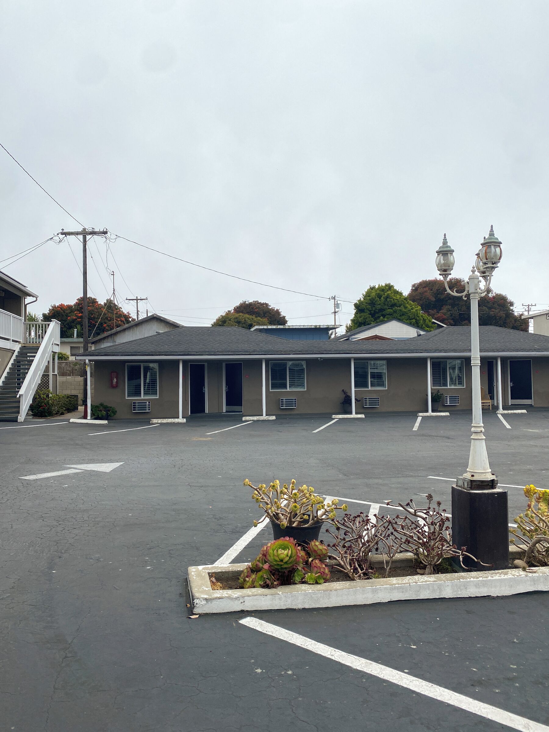 A building with a parking lot, a staircase, and a lamp post.
