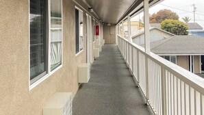 En korridor med balkon, flere vinduer og en betondæk.