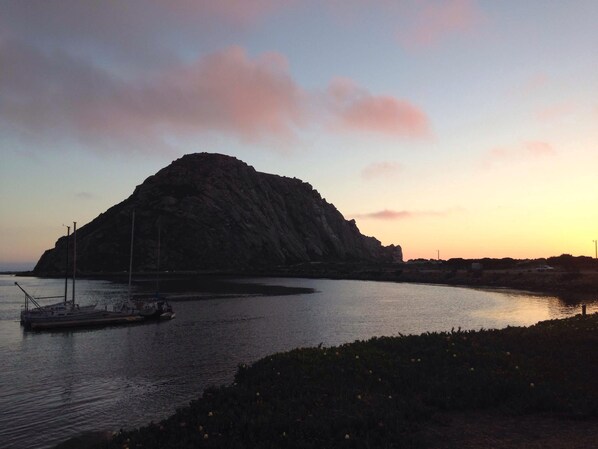 A coastal scene with a large rock formation, calm water, and a small boat.