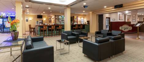 A lobby with sofas, a bar area, and a reception desk.