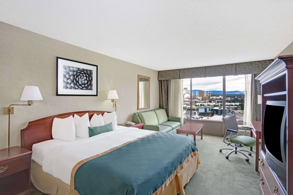 A hotel room with a bed, a sofa, a desk, and a TV.