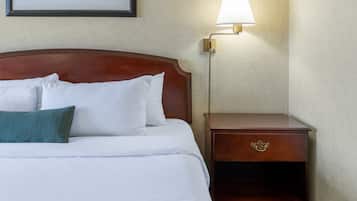 A neatly made bed with white and teal pillows, a wooden headboard, and a bedside table with a lamp.