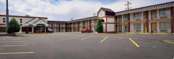 A motel with a central parking lot, multiple-story buildings, and a clear sky. - SureStay by Best Western Miles City (Miles City)