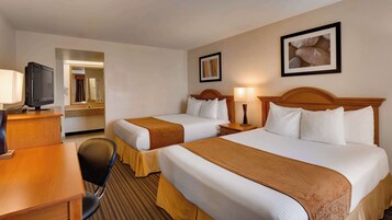 A hotel room with two beds, a desk, a chair, a television, and a framed picture on the wall.