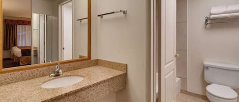 A bathroom with a granite countertop sink, a mirror, a towel rack, and a toilet.
