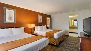A hotel room with two beds, a TV, and a bathroom visible through an open door. - SureStay by Best Western Miles City (Miles City)